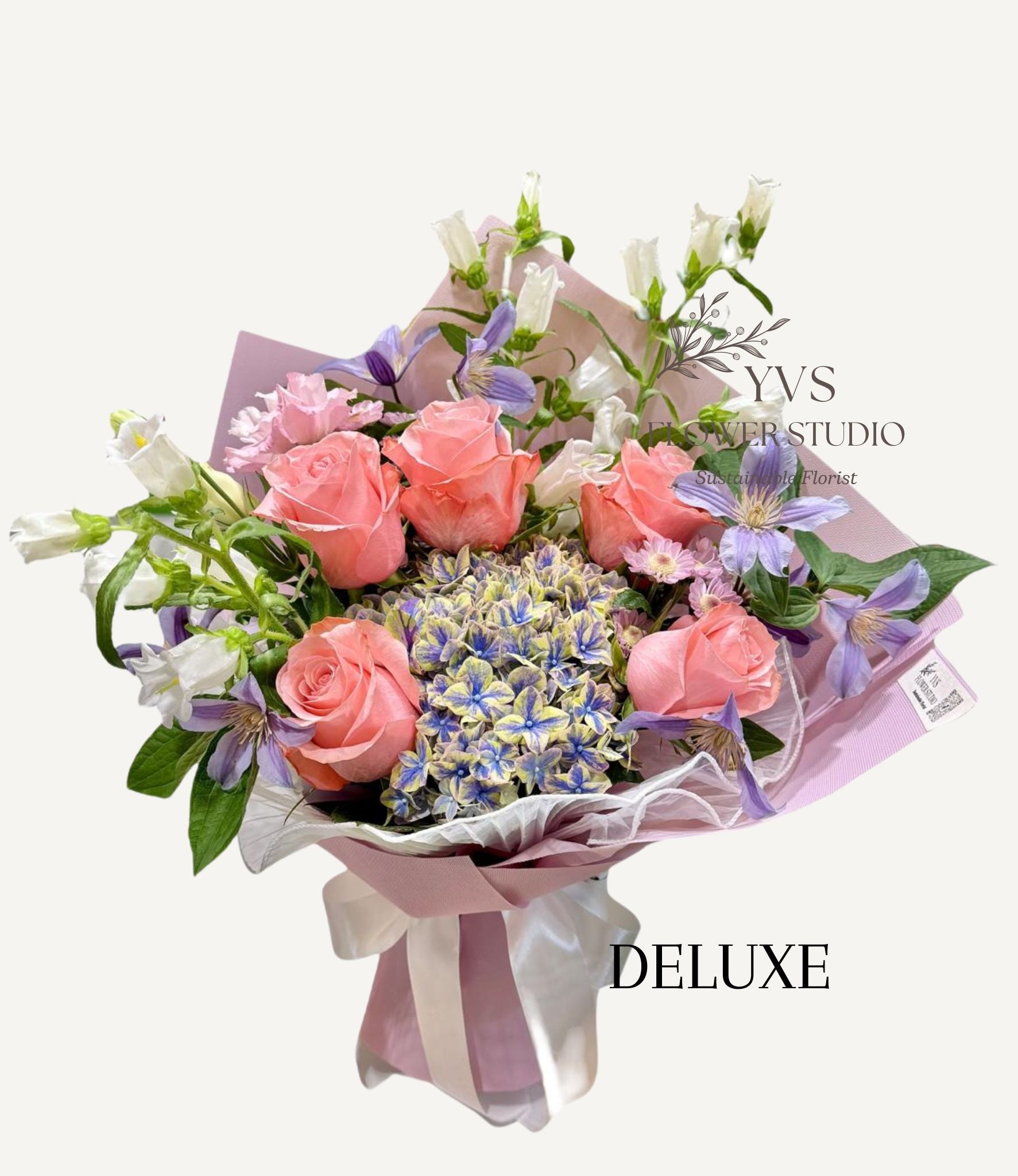 Bouquet of blue two tone hydrangea and other flowers wrapped in lilac paper with 'VS Florist Studio' branding.