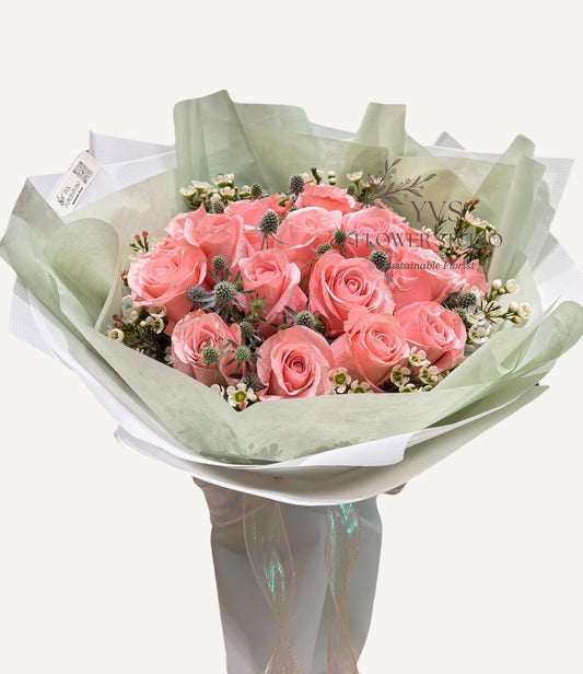Bouquet of pink gorgeous roses wrapped in green and white paper. 